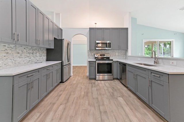 kitchen with tasteful backsplash, appliances with stainless steel finishes, light hardwood / wood-style flooring, gray cabinets, and sink