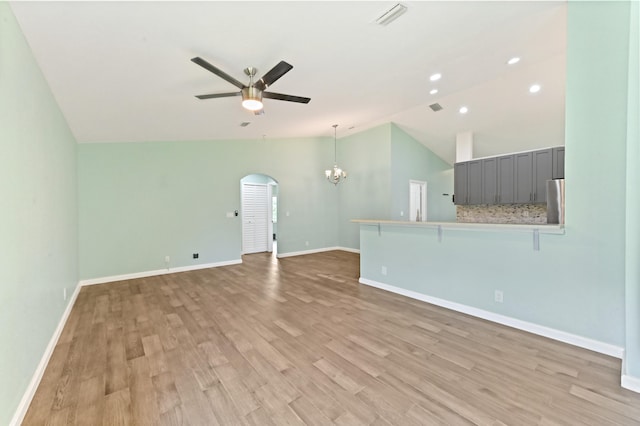 unfurnished living room featuring vaulted ceiling, light hardwood / wood-style flooring, and ceiling fan with notable chandelier