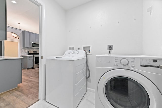 clothes washing area featuring washer and clothes dryer and light wood-type flooring