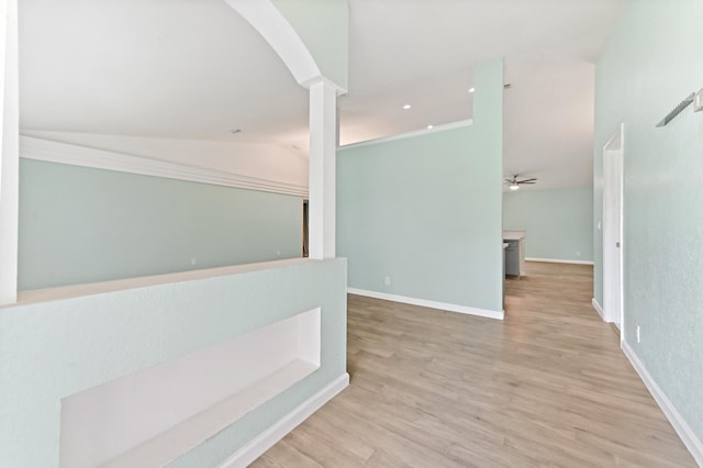 hallway with light hardwood / wood-style flooring, vaulted ceiling, and decorative columns