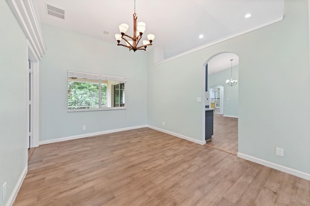 empty room featuring light hardwood / wood-style flooring, high vaulted ceiling, a notable chandelier, and crown molding