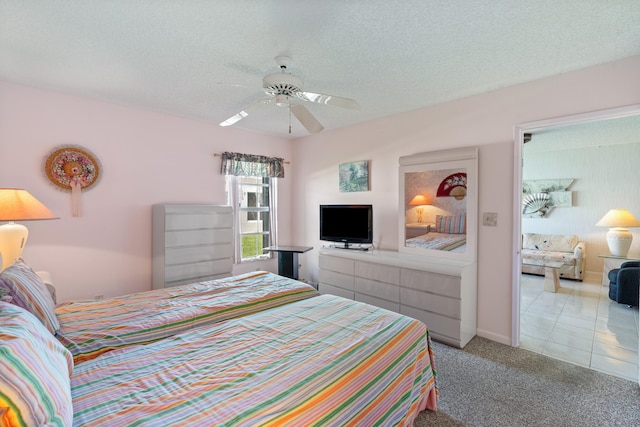 bedroom with a textured ceiling, light colored carpet, and ceiling fan