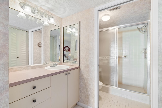 bathroom featuring a shower with door, a textured ceiling, toilet, vanity, and tile patterned floors