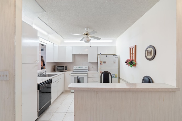 kitchen with white appliances, light tile patterned flooring, a textured ceiling, kitchen peninsula, and white cabinetry