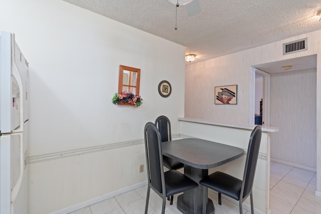 dining space featuring a textured ceiling and light tile patterned floors