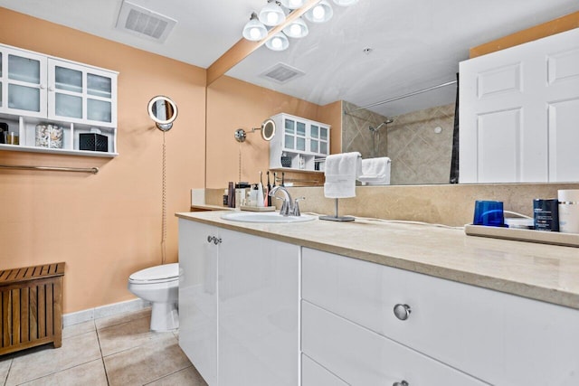 bathroom featuring tile patterned floors, toilet, vanity, a tile shower, and tasteful backsplash