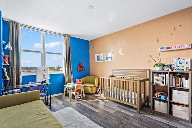 bedroom featuring a textured ceiling, hardwood / wood-style flooring, and a crib