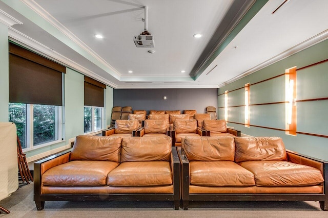 carpeted home theater room with ornamental molding and a tray ceiling