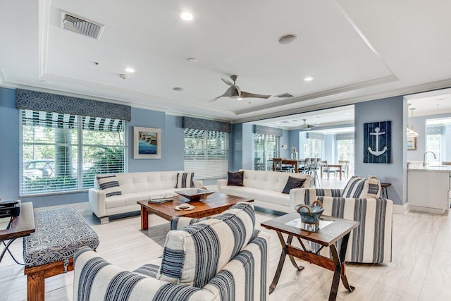 living room featuring crown molding, ceiling fan, sink, and a raised ceiling