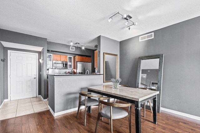 dining space featuring hardwood / wood-style floors, track lighting, and a textured ceiling