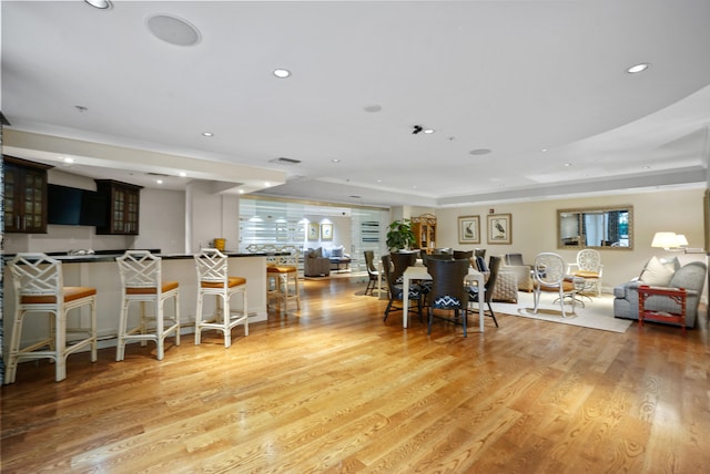 living room featuring a raised ceiling and light wood-type flooring