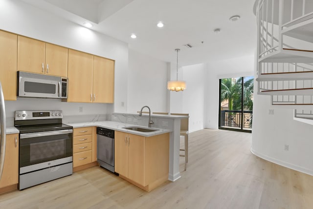 kitchen with kitchen peninsula, light brown cabinets, sink, light hardwood / wood-style floors, and stainless steel appliances