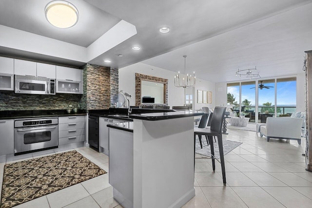 kitchen featuring backsplash, appliances with stainless steel finishes, a kitchen bar, sink, and kitchen peninsula