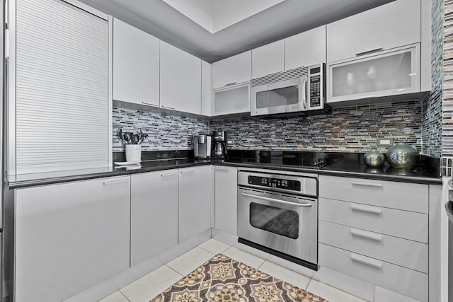 kitchen with stainless steel appliances, white cabinetry, light tile patterned floors, and decorative backsplash