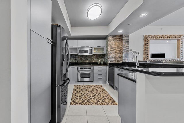 kitchen featuring white cabinets, sink, light tile patterned flooring, backsplash, and appliances with stainless steel finishes