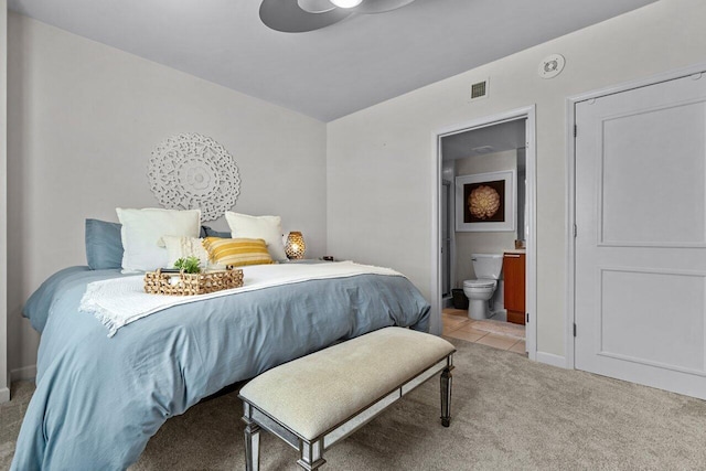 bedroom featuring light carpet, ceiling fan, and ensuite bath