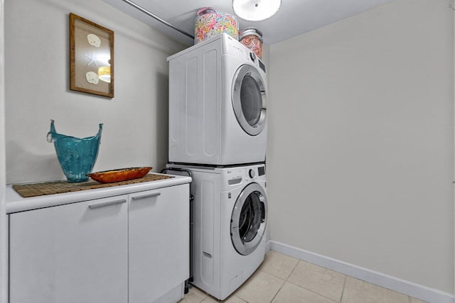 washroom featuring cabinets, light tile patterned floors, and stacked washer / drying machine