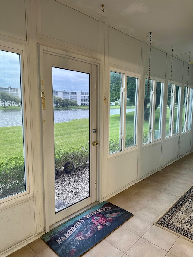 doorway to outside featuring a water view and light tile patterned floors