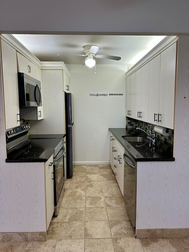 kitchen with appliances with stainless steel finishes, dark stone countertops, sink, and ceiling fan