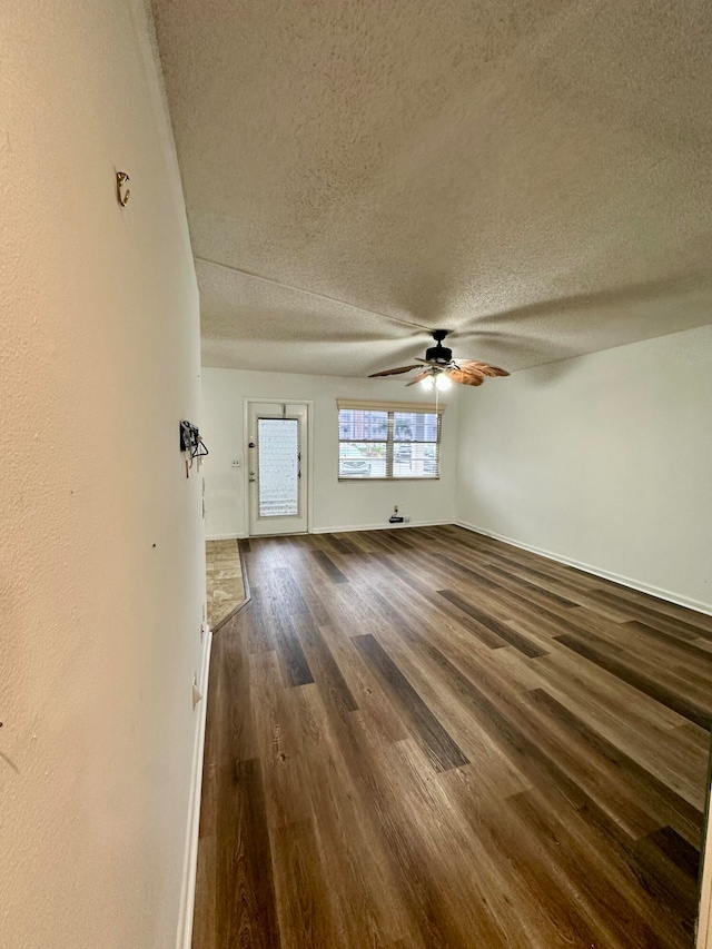 unfurnished living room featuring ceiling fan, a textured ceiling, and dark hardwood / wood-style flooring