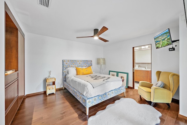 bedroom featuring baseboards, visible vents, wood finished floors, ceiling fan, and ensuite bath