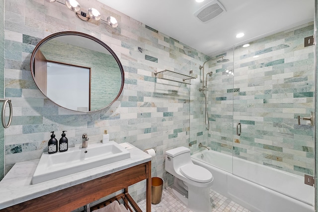 bathroom featuring shower / bath combination with glass door, tile patterned flooring, visible vents, toilet, and tile walls