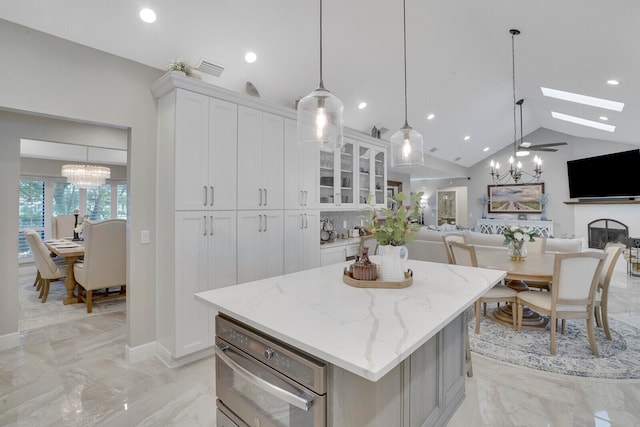 kitchen with a center island, white cabinetry, decorative light fixtures, and a skylight