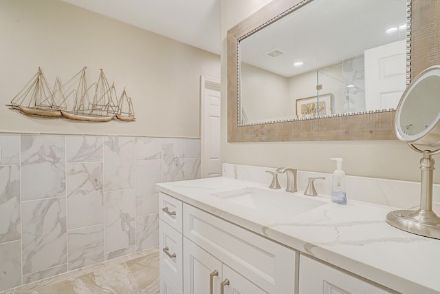 bathroom with vanity, a shower, and tile walls