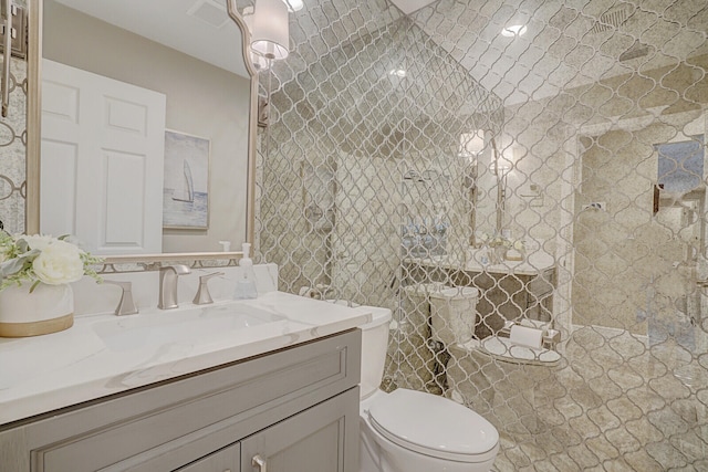 bathroom featuring vanity, a tile shower, and toilet