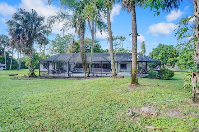 rear view of property with a lanai and a lawn