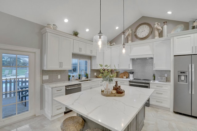 kitchen with a kitchen island, appliances with stainless steel finishes, decorative light fixtures, white cabinetry, and premium range hood