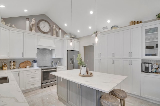 kitchen with lofted ceiling, appliances with stainless steel finishes, decorative light fixtures, and white cabinets