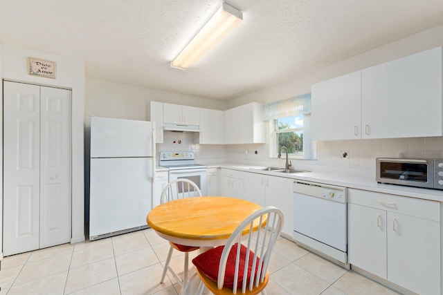 kitchen with backsplash, sink, light tile patterned floors, white cabinets, and white appliances