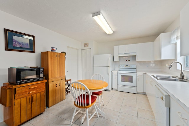 kitchen with white appliances, light tile patterned flooring, sink, and white cabinets