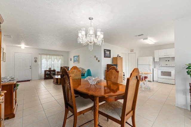 dining area featuring a notable chandelier, a textured ceiling, and light tile patterned floors