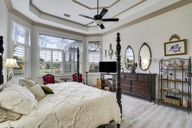 bedroom with ceiling fan, crown molding, light hardwood / wood-style flooring, and a raised ceiling