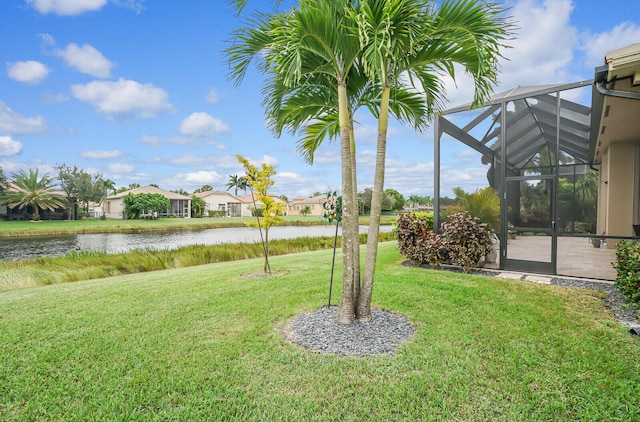 view of yard with a lanai and a water view