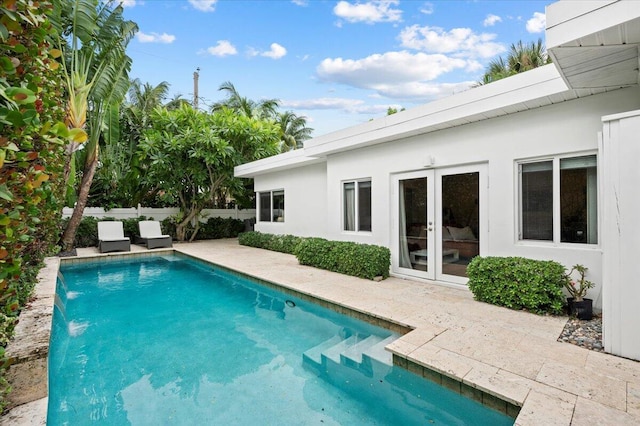 view of swimming pool with pool water feature, a patio area, and french doors