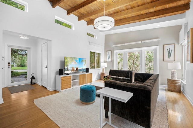 living room featuring beamed ceiling, a high ceiling, light hardwood / wood-style flooring, and wood ceiling