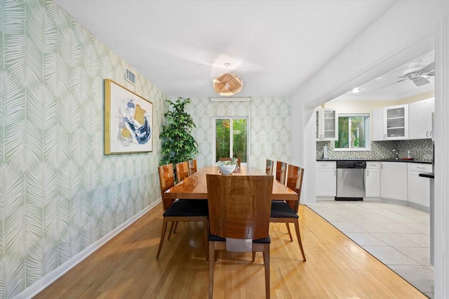 dining space with ceiling fan, crown molding, sink, and light hardwood / wood-style flooring