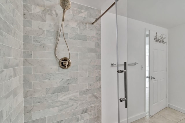 bathroom with a tile shower and tile patterned flooring