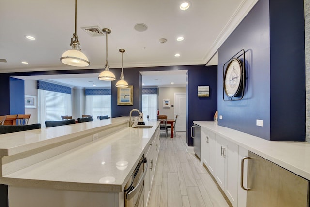 kitchen with a spacious island, white cabinetry, ornamental molding, pendant lighting, and sink