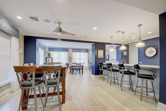 dining area featuring light hardwood / wood-style flooring, ceiling fan, and crown molding