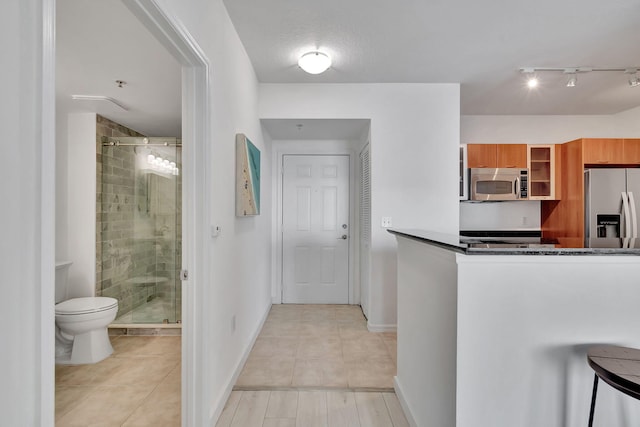 kitchen featuring dark stone countertops, light tile patterned floors, appliances with stainless steel finishes, and a textured ceiling