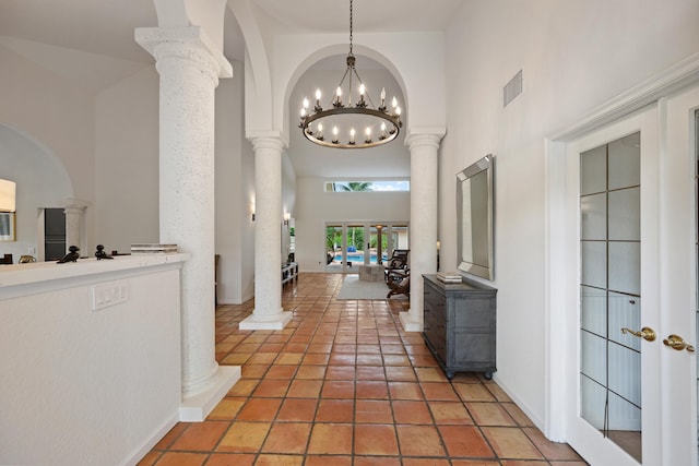 hall featuring ornate columns, french doors, high vaulted ceiling, and a notable chandelier