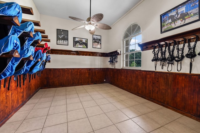 unfurnished room featuring ceiling fan, wood walls, and light tile patterned flooring