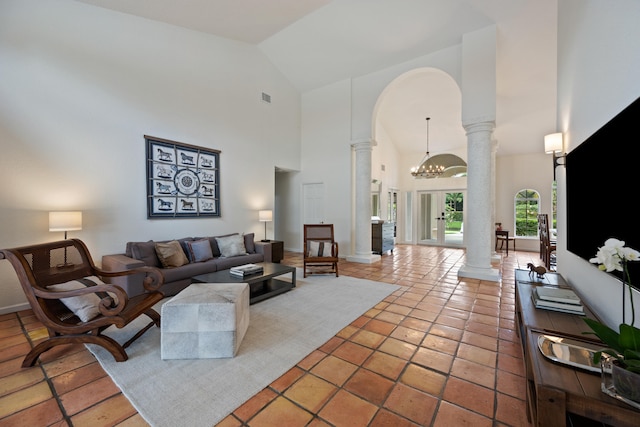 tiled living room featuring a notable chandelier, high vaulted ceiling, and decorative columns