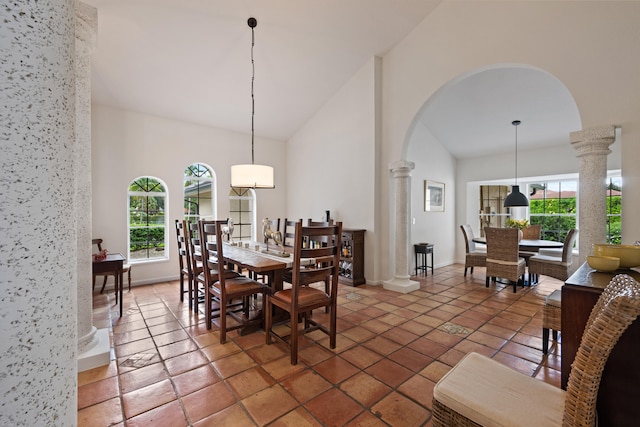 dining room featuring dark tile patterned floors, decorative columns, high vaulted ceiling, and a wealth of natural light