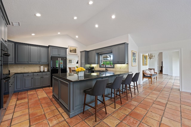 kitchen with a kitchen bar, tasteful backsplash, ceiling fan, dark stone countertops, and gray cabinets