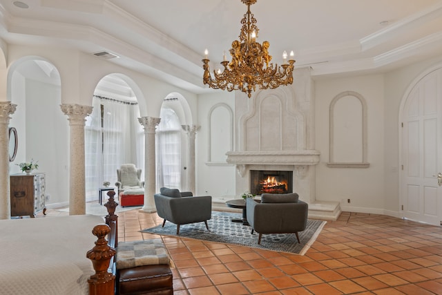 bedroom featuring tile patterned floors, ornamental molding, a tray ceiling, a large fireplace, and decorative columns